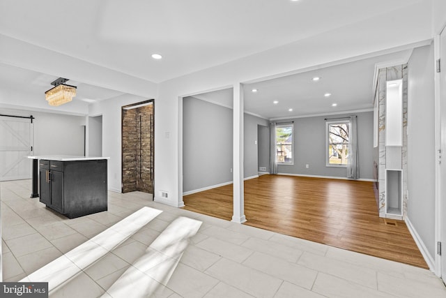 unfurnished living room with recessed lighting, a barn door, baseboards, and ornamental molding