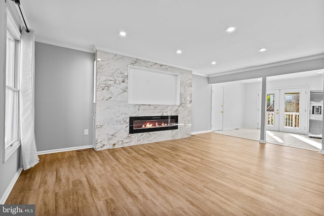 unfurnished living room featuring recessed lighting, wood finished floors, a high end fireplace, and crown molding