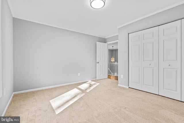 unfurnished bedroom with a closet, carpet flooring, crown molding, and baseboards