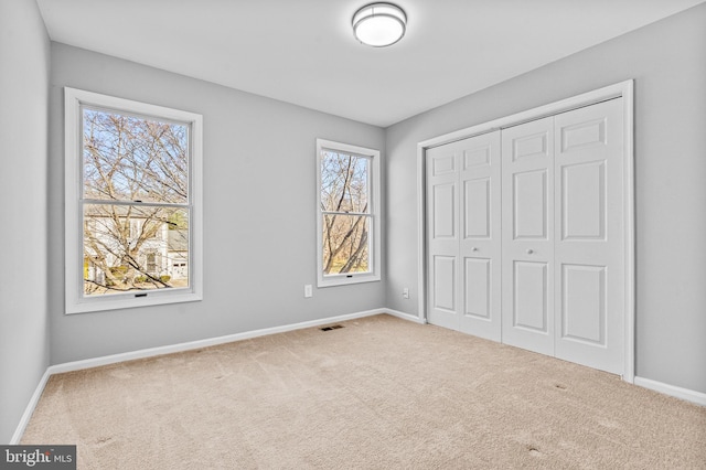 unfurnished bedroom with carpet flooring, baseboards, visible vents, and a closet