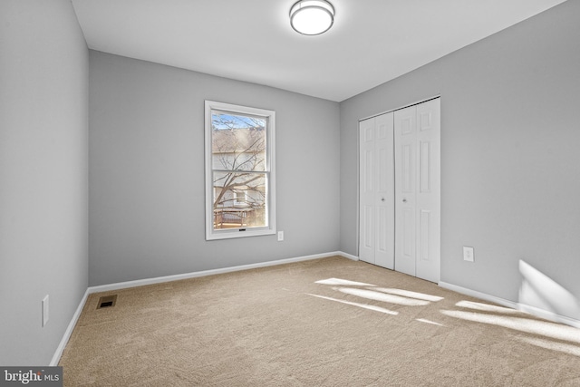 unfurnished bedroom featuring carpet flooring, visible vents, a closet, and baseboards