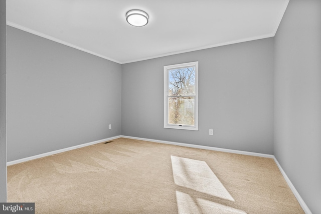 carpeted spare room with visible vents, baseboards, and ornamental molding