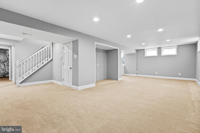 below grade area featuring visible vents, baseboards, recessed lighting, stairs, and light colored carpet