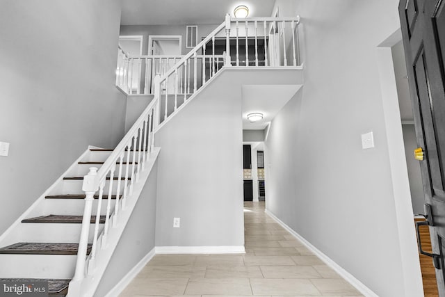 stairs featuring a high ceiling and baseboards