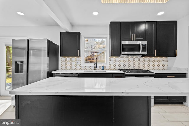 kitchen with backsplash, appliances with stainless steel finishes, dark cabinetry, and a sink