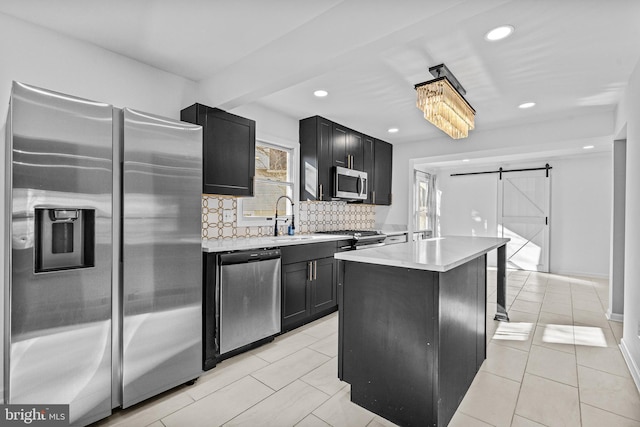 kitchen with stainless steel appliances, light countertops, a barn door, and dark cabinets