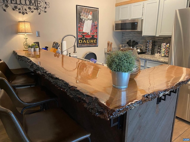 2225 Tanners Rdg, Condos, Wintergreen Resort, VA 22967 - kitchen featuring stainless steel appliances, a kitchen bar, light wood finished floors, backsplash, and white cabinetry