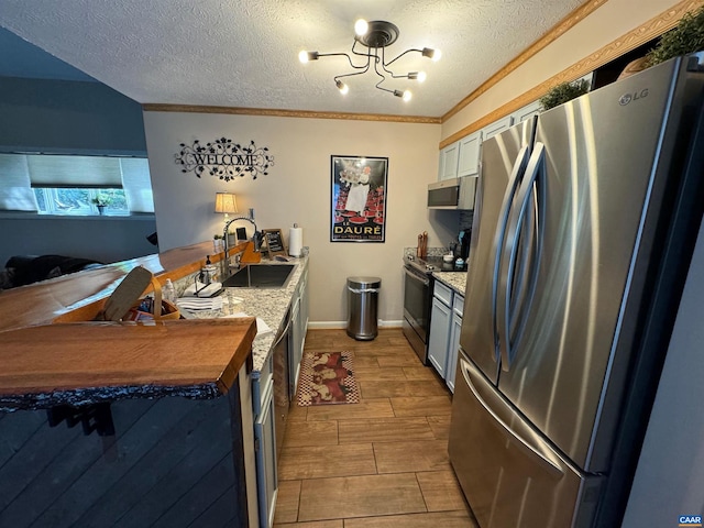 kitchen with a textured ceiling, wood tiled floor, appliances with stainless steel finishes, and a sink