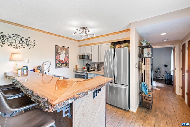 2225 Tanners Rdg, Condos, Wintergreen Resort, VA 22967 - kitchen featuring stainless steel appliances, a kitchen breakfast bar, a sink, decorative backsplash, and light wood-type flooring
