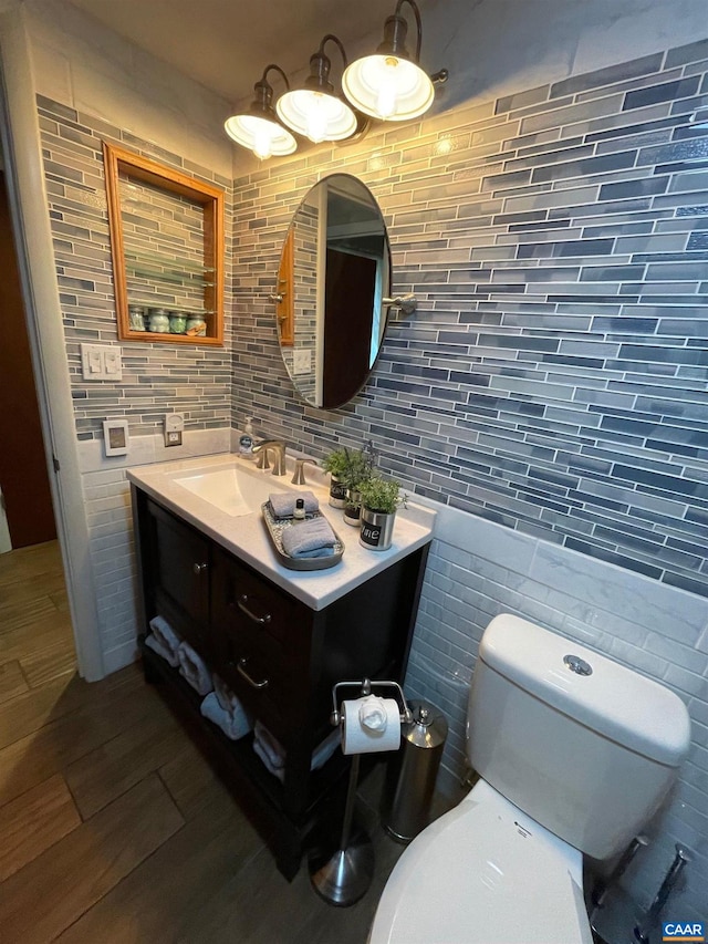 bathroom featuring vanity, wood finished floors, tile walls, toilet, and backsplash