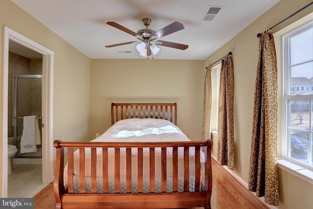 bedroom featuring light tile patterned flooring, visible vents, connected bathroom, and ceiling fan