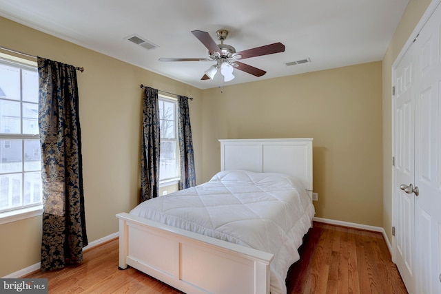 bedroom with light wood-type flooring, visible vents, baseboards, and a closet