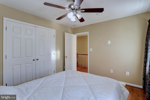 bedroom featuring visible vents, baseboards, wood finished floors, a closet, and a ceiling fan