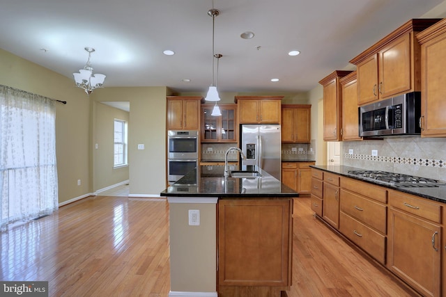 kitchen featuring brown cabinets, appliances with stainless steel finishes, light wood-style flooring, and a sink