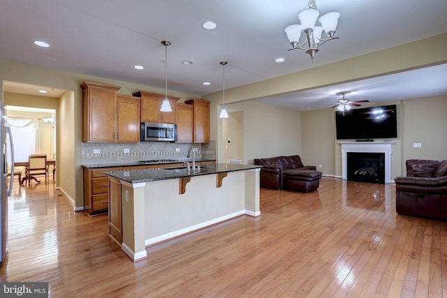 kitchen featuring stainless steel microwave, a breakfast bar area, brown cabinets, and light wood-type flooring