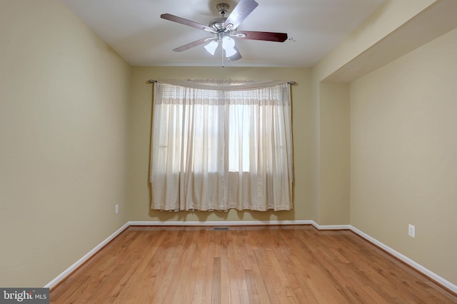 empty room featuring ceiling fan, visible vents, baseboards, and wood finished floors