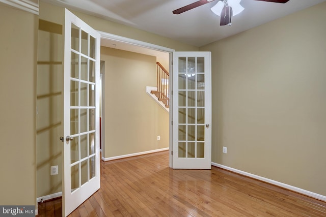 spare room featuring a ceiling fan, baseboards, stairs, french doors, and wood-type flooring