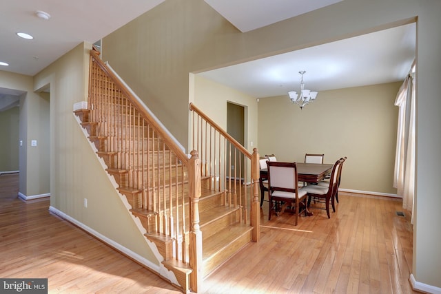 stairs with hardwood / wood-style floors, a notable chandelier, recessed lighting, and baseboards