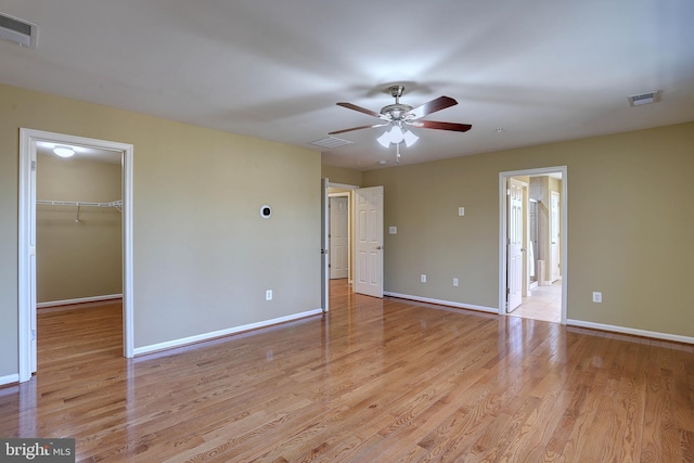 empty room featuring light wood-type flooring, visible vents, baseboards, and a ceiling fan