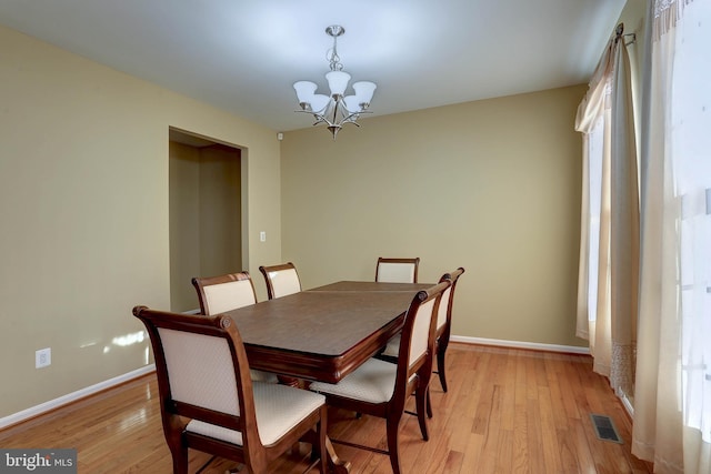 dining space featuring a chandelier, visible vents, light wood-type flooring, and baseboards