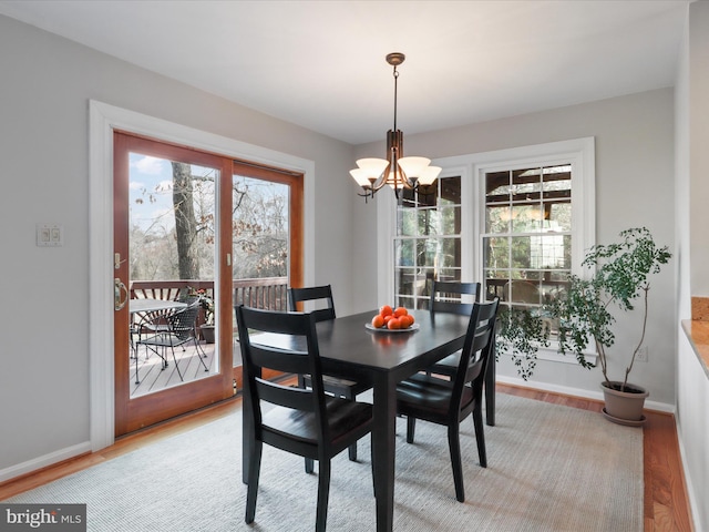 dining room featuring an inviting chandelier, baseboards, and light wood-type flooring