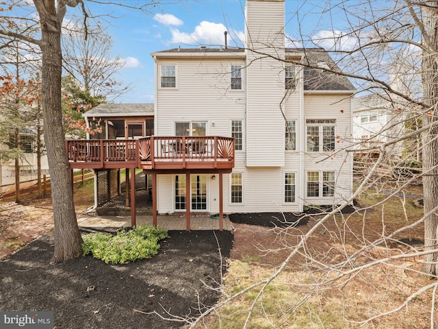 rear view of property with a deck, a patio, and a chimney