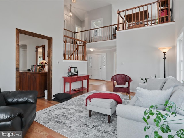 living area featuring stairway, arched walkways, a high ceiling, and wood finished floors