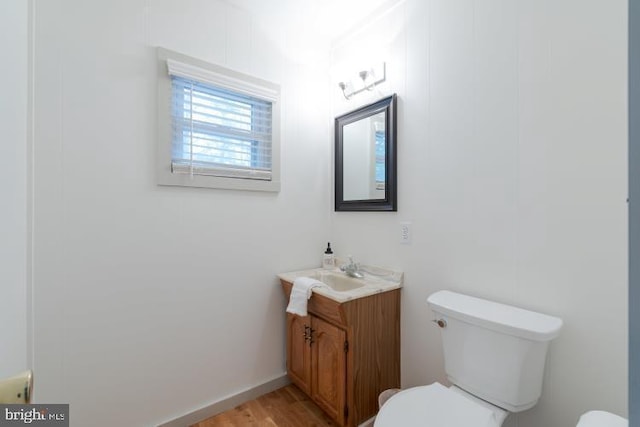 bathroom featuring toilet, vanity, baseboards, and wood finished floors