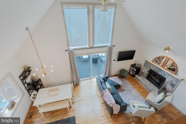 living area with high vaulted ceiling, light wood-style flooring, and a fireplace