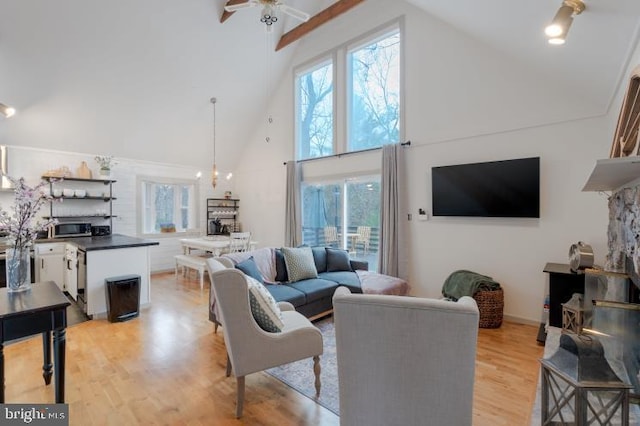 living room with ceiling fan, light wood-style flooring, and high vaulted ceiling