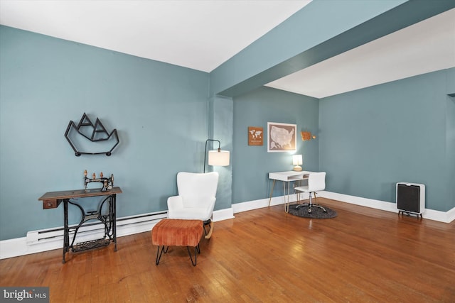 sitting room with a baseboard heating unit, wood finished floors, and baseboards