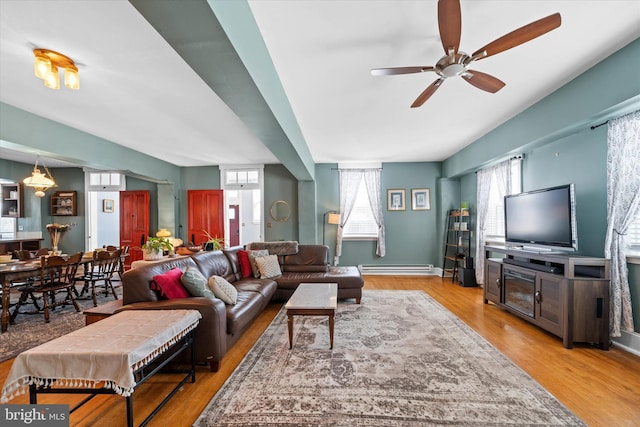 living room with ceiling fan, a baseboard heating unit, baseboards, and wood finished floors