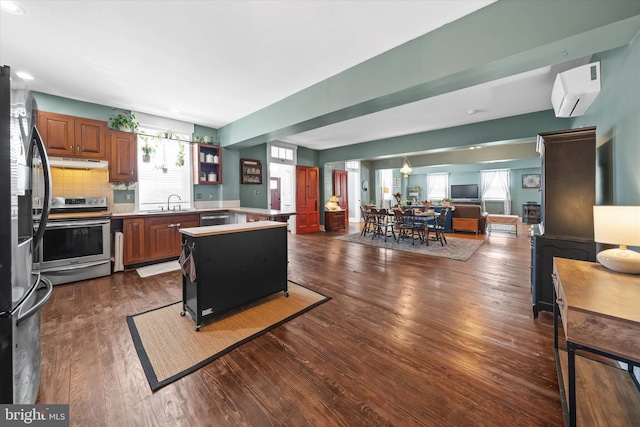 kitchen with under cabinet range hood, a wealth of natural light, dark wood-style flooring, and appliances with stainless steel finishes