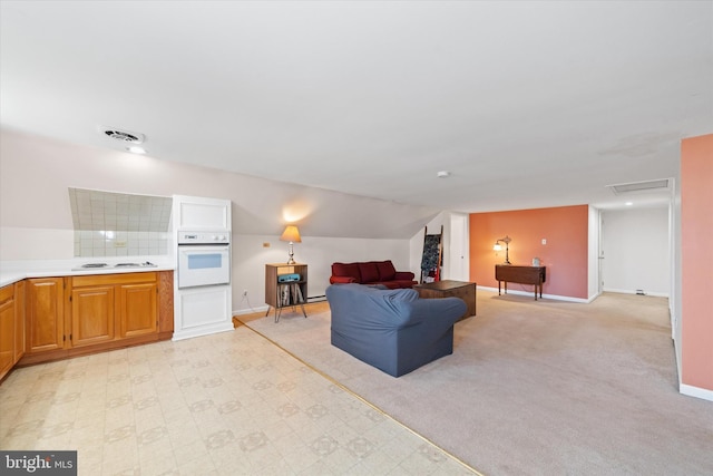 living area with visible vents, baseboards, attic access, lofted ceiling, and light carpet