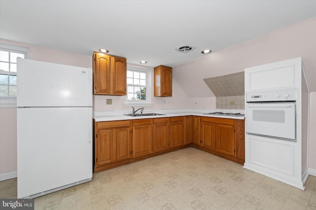 kitchen featuring visible vents, a sink, white appliances, light countertops, and light floors