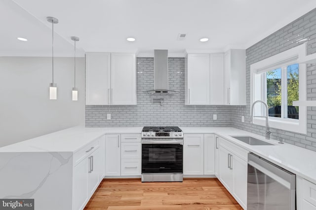 kitchen featuring a sink, stainless steel appliances, white cabinetry, wall chimney range hood, and light wood-type flooring