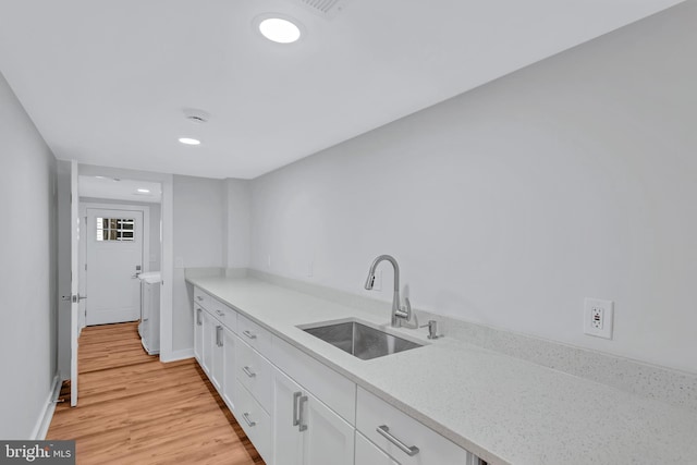 kitchen featuring baseboards, light wood-type flooring, recessed lighting, white cabinets, and a sink