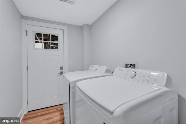 clothes washing area with laundry area, light wood-style flooring, separate washer and dryer, and visible vents