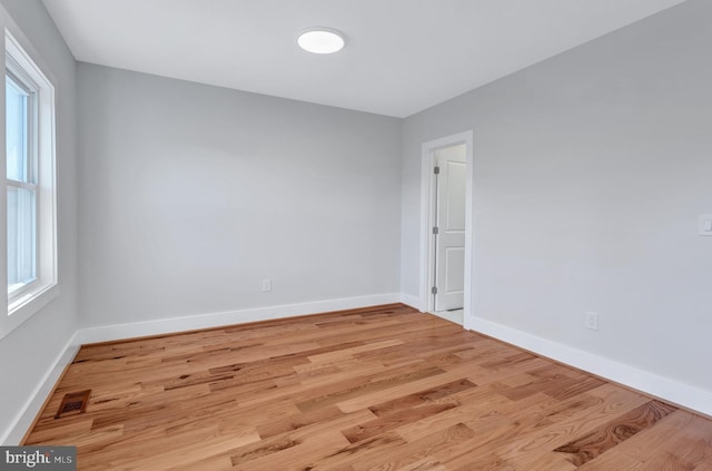 spare room featuring visible vents, wood finished floors, baseboards, and a wealth of natural light