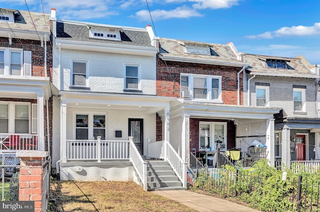 townhome / multi-family property featuring mansard roof, brick siding, covered porch, and roof with shingles