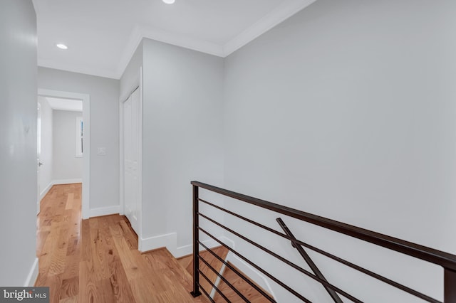 corridor featuring an upstairs landing, crown molding, light wood-type flooring, and baseboards