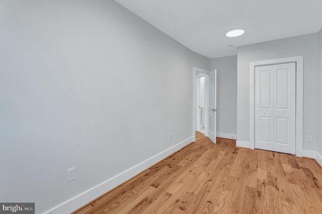 unfurnished bedroom featuring a closet, baseboards, and light wood finished floors