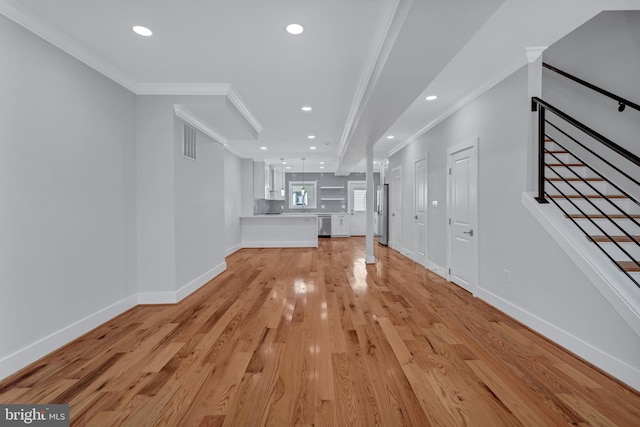 unfurnished living room featuring stairway, baseboards, visible vents, light wood finished floors, and ornamental molding