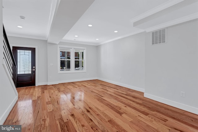 foyer featuring visible vents, baseboards, light wood-style floors, and ornamental molding