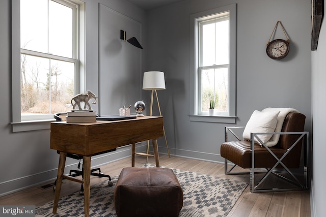 living area with baseboards, a healthy amount of sunlight, and wood finished floors