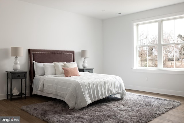 bedroom with visible vents, wood finished floors, and baseboards