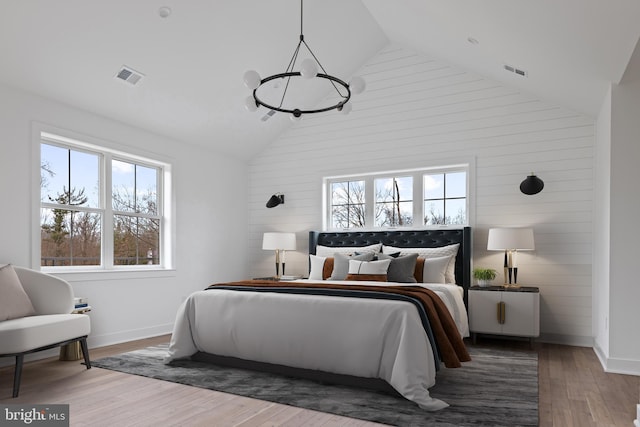 bedroom with high vaulted ceiling, wood finished floors, visible vents, and baseboards