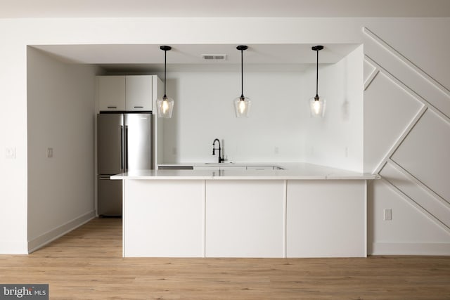 kitchen with hanging light fixtures, high end refrigerator, a peninsula, and visible vents