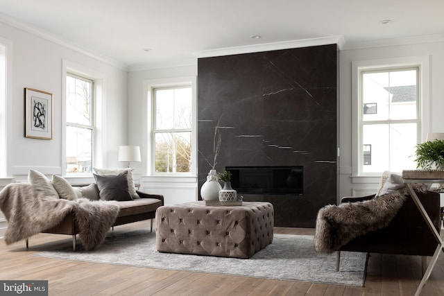 living area featuring a premium fireplace, wood-type flooring, and ornamental molding