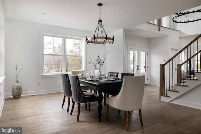 dining space with stairs, wood finished floors, baseboards, and a chandelier